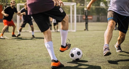 Close up of two men's feet playing football on a football pitch