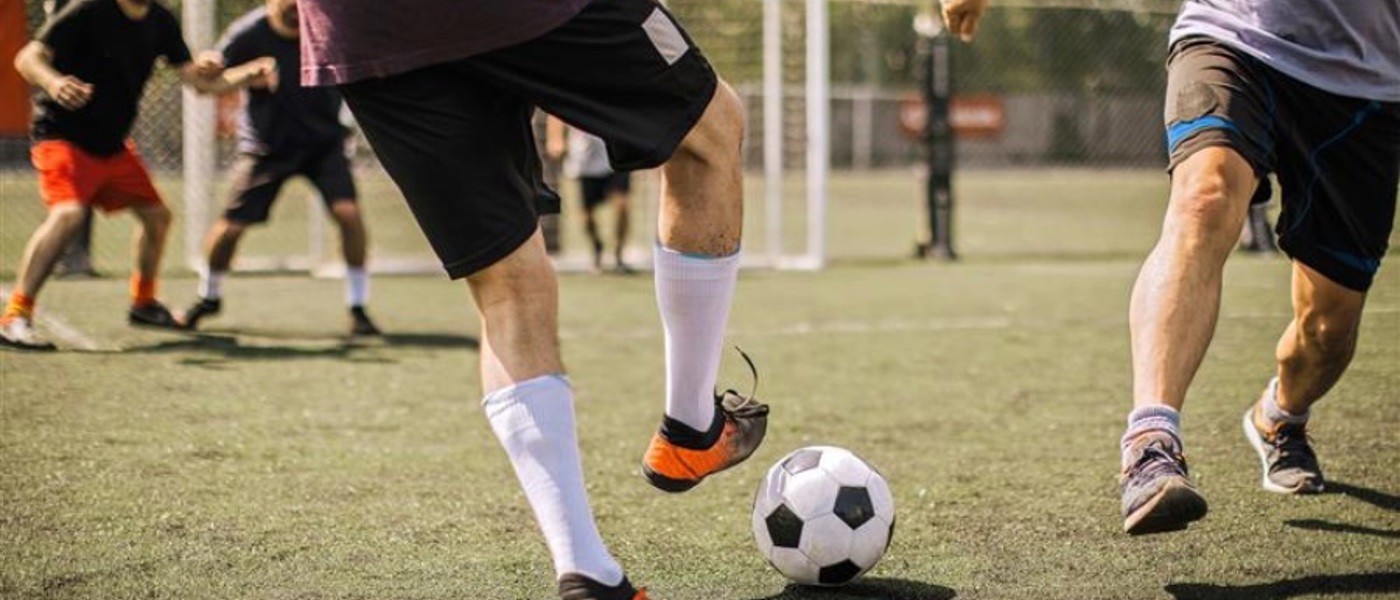 Close up of two men's feet playing football on a football pitch