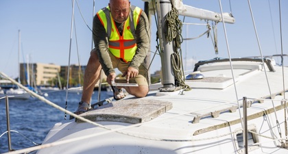 A man in a high vis vest repairing a ship at sea