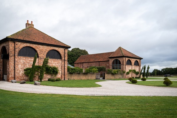 External view of a converted barn with lawns in front 