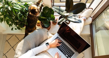 Aerial view of a woman sitting with her feet up at home and a laptop on her lap