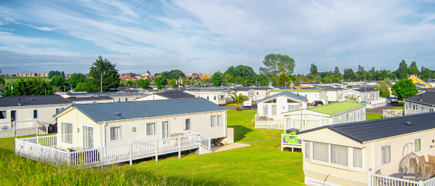 White static caravans with picket fences and green lawn beneath them
