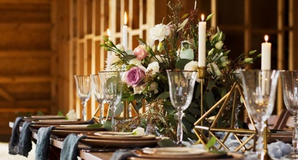 Wedding table with a spray of pink roses in the centre and wine glasses