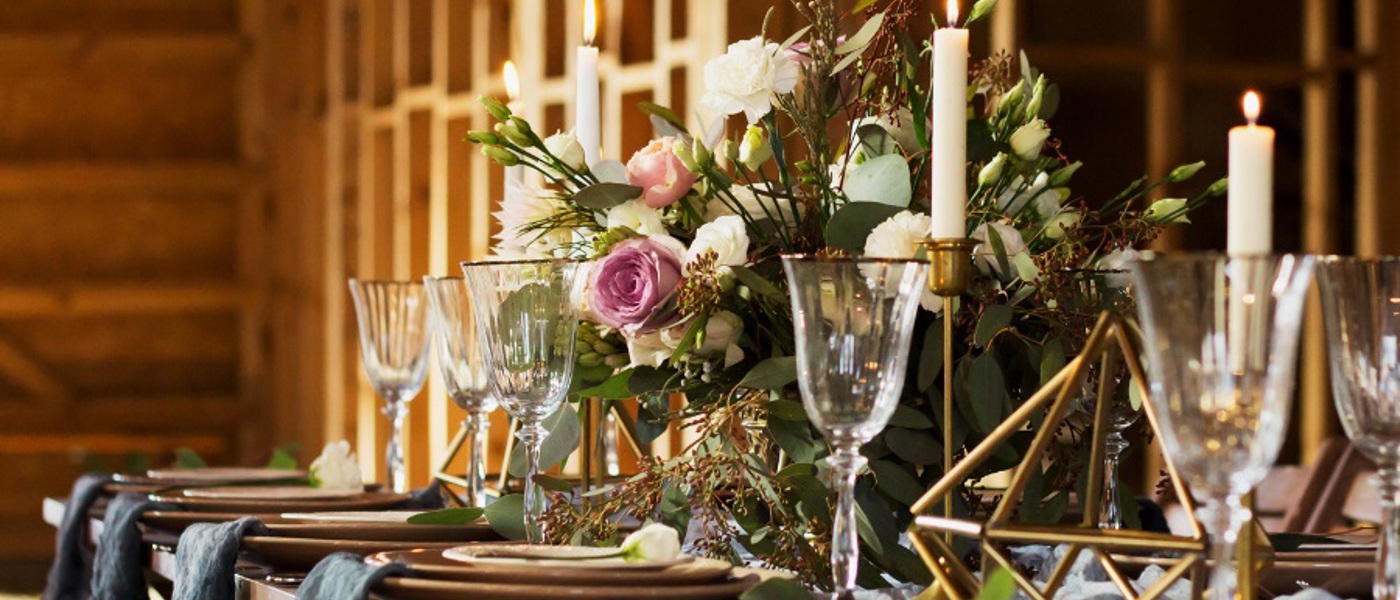 Wedding table with a spray of pink roses in the centre and wine glasses