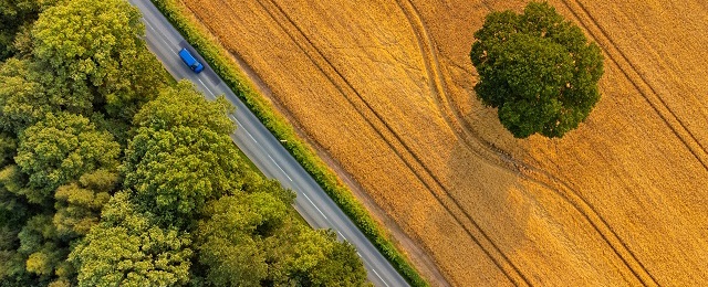 Blue car driving on country lane