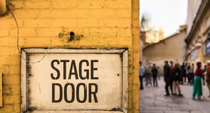 Close up of a yellow stage door sign on a brick wall